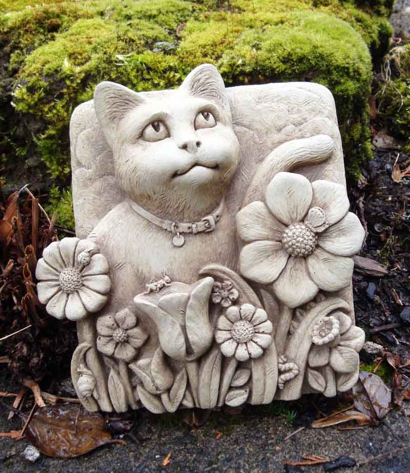 Smitten Kitten plaque set in a garden bed in front of a moss covered rock